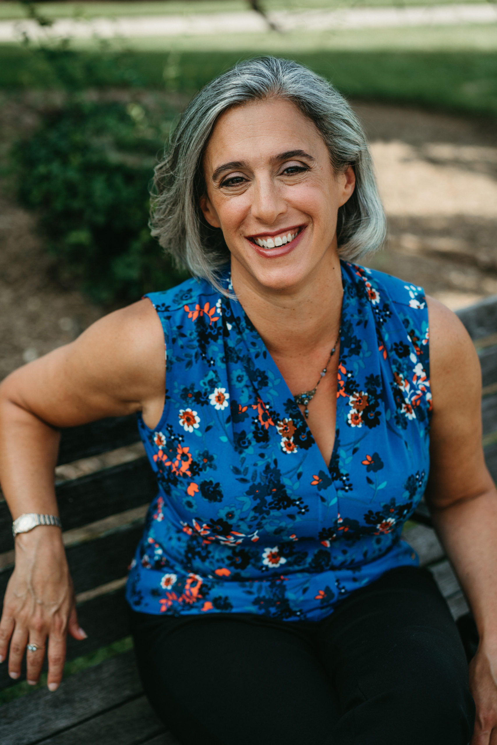 Full Color headshot of Director Julianna Dodson of Radically Rural.  She is standing next to a large industrial window in a nondescript commercial building, leaning on the sill and smiling directly into the camera.